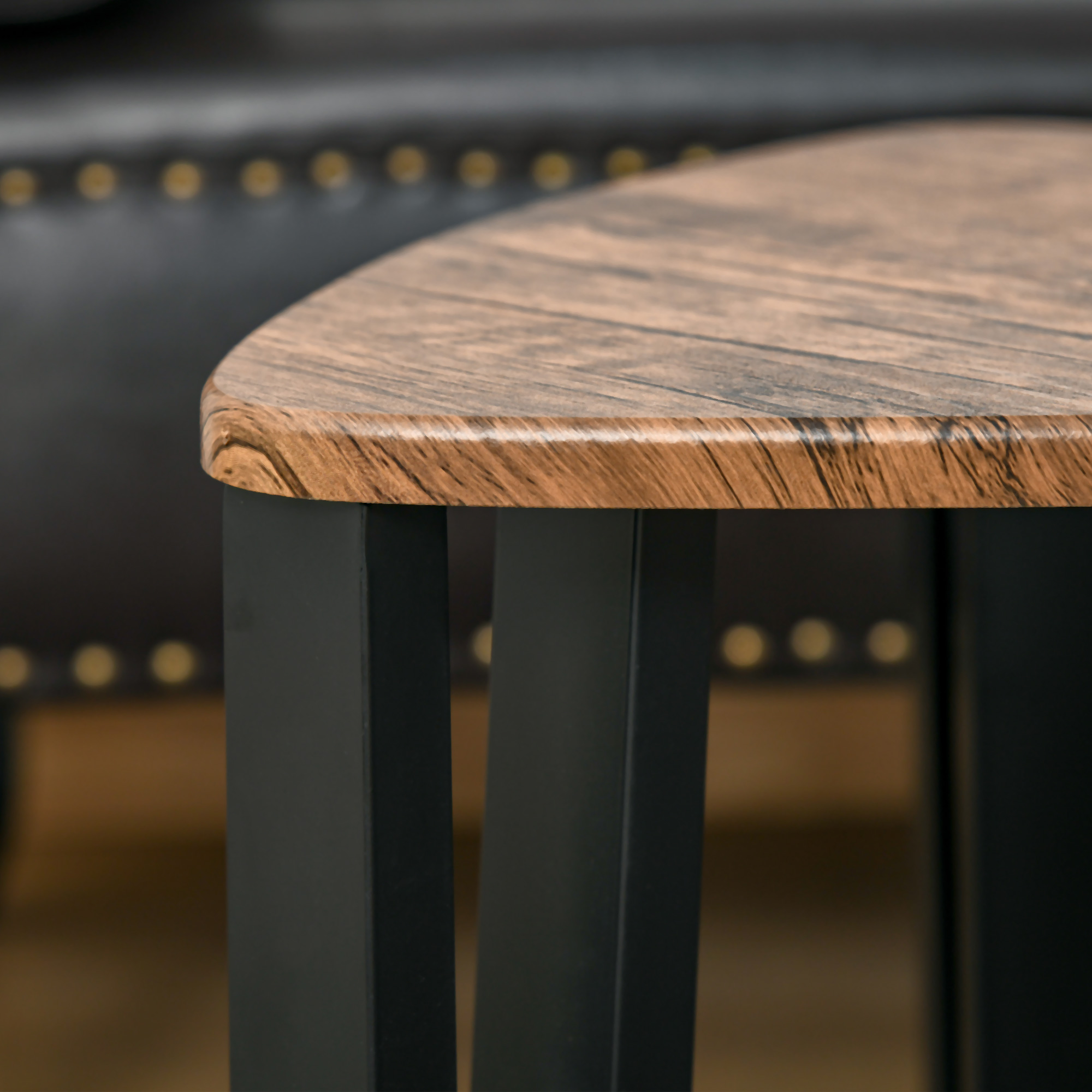 Nahaufnahme einer Holztisch-Ecke mit schwarzen Beinen. Der Hintergrund ist unscharf.