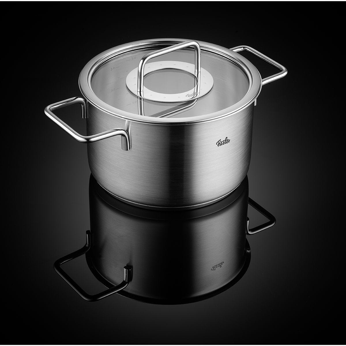 Pentola in acciaio inox con coperchio in vetro, su una superficie nera riflettente.