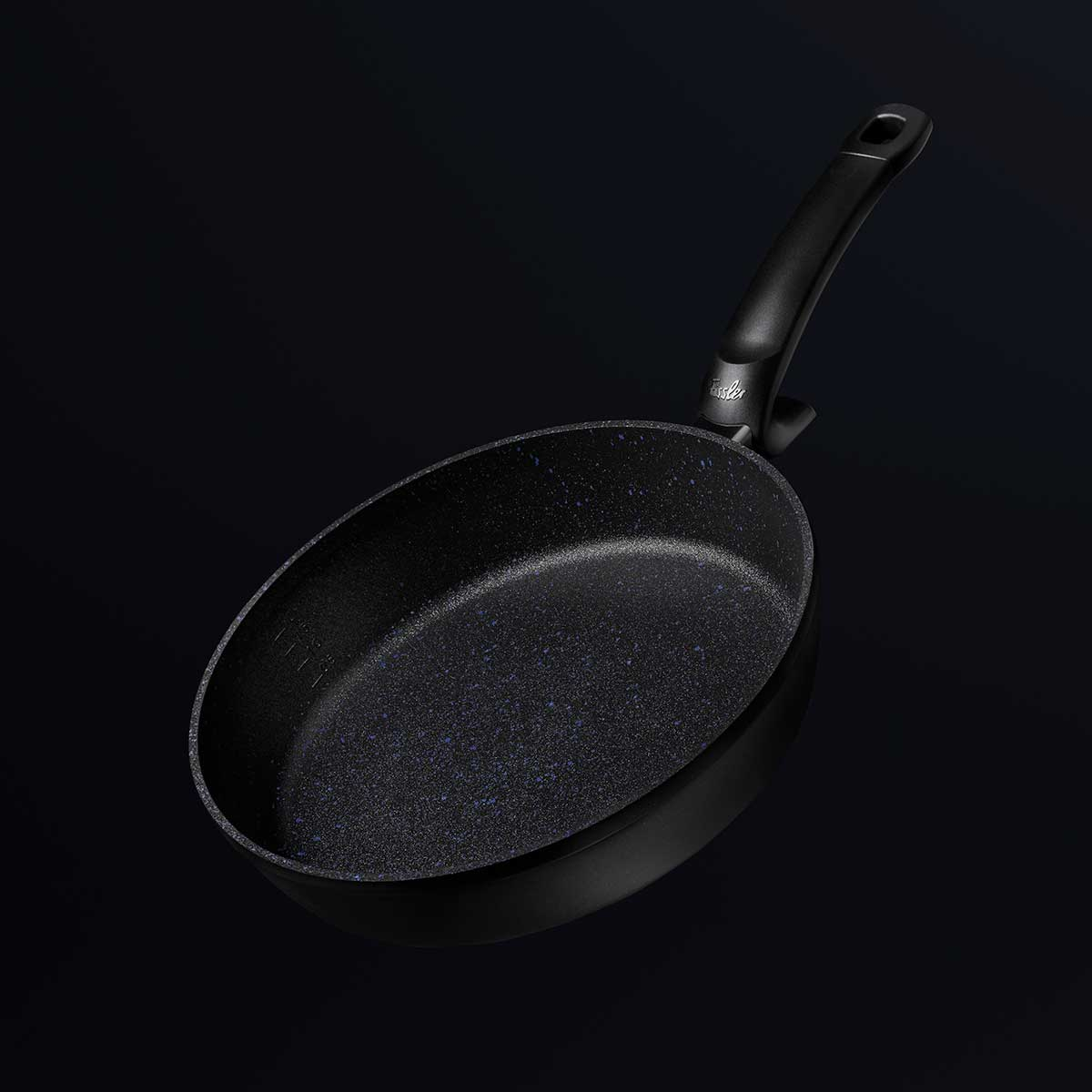 Una padella nera con manico nero, su sfondo nero. La padella ha una superficie strutturata.