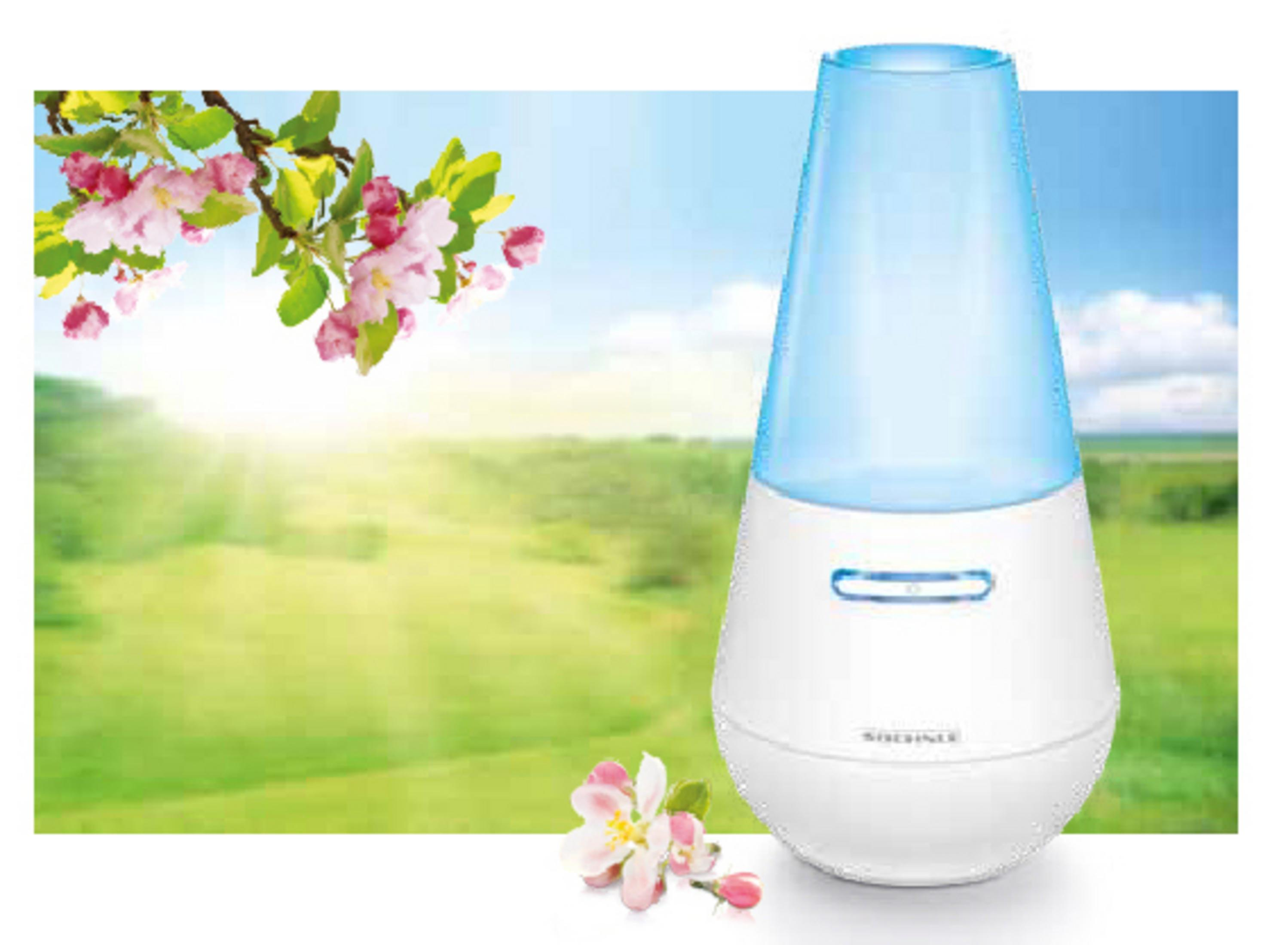 Un diffusore bianco con coperchio blu su una superficie, con sfondo di prato verde.