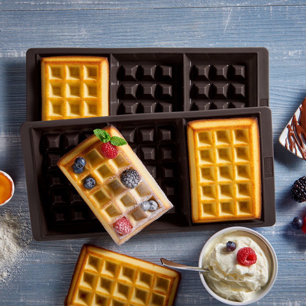 Gofry na tacy. Jeden gofr z jagodami i bitą śmietaną. Drugi bez dodatków.