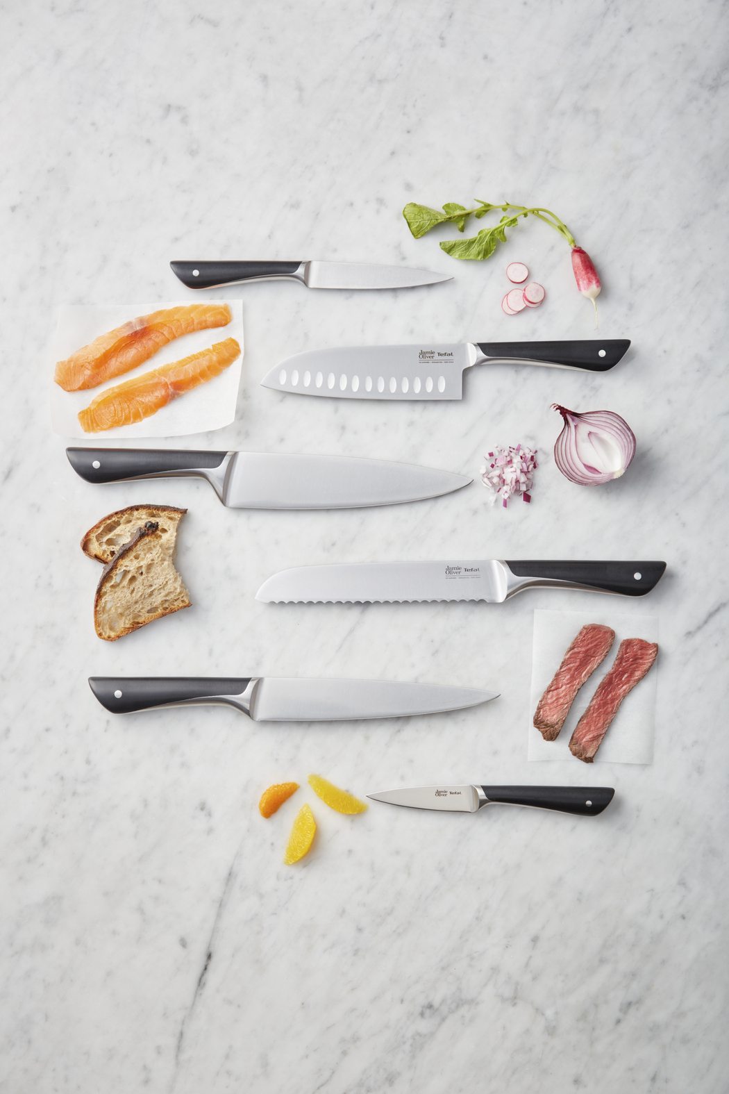 Coltelli e ingredienti: salmone, cipolla, pane, bistecca e fette d'arancia.