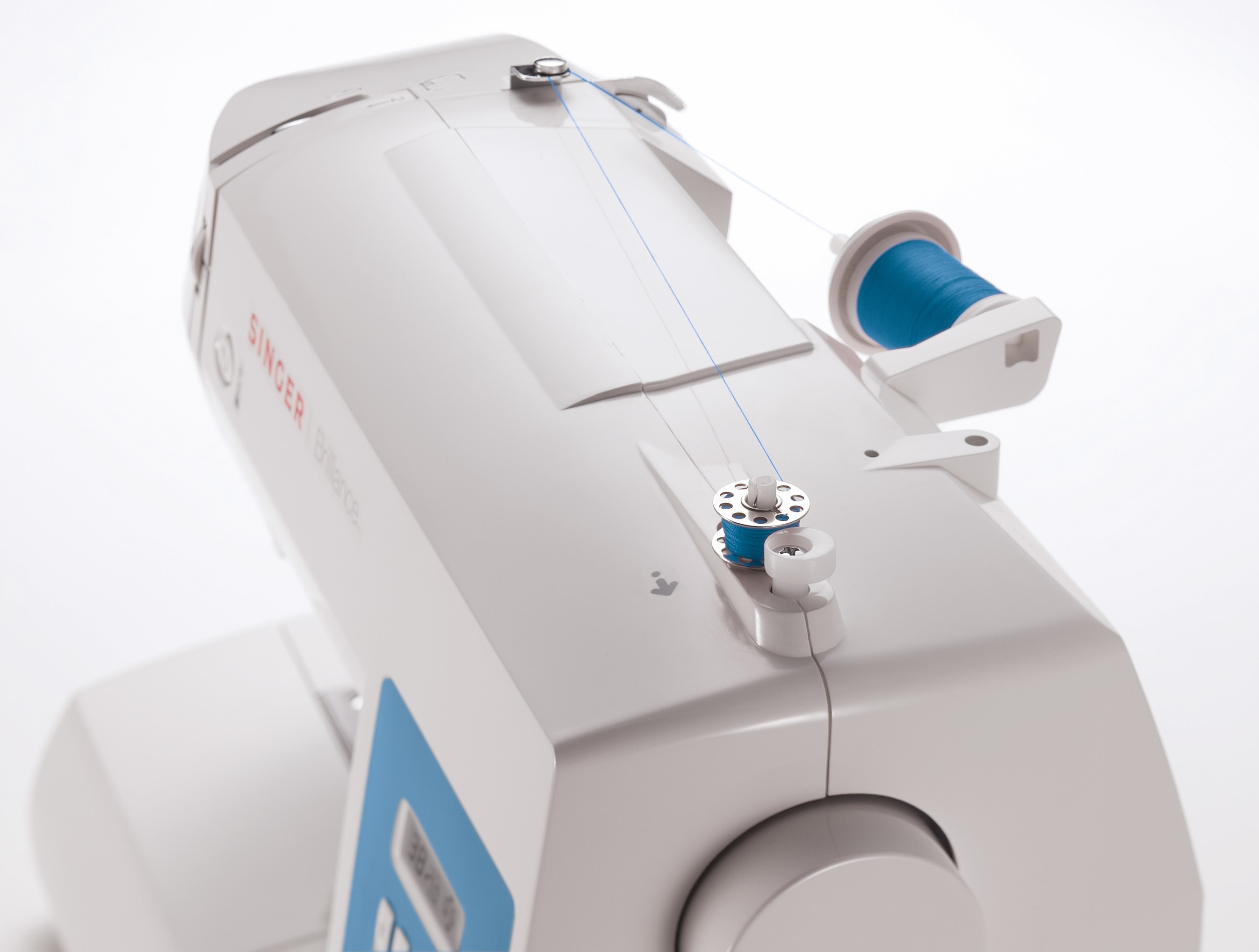 Biała i niebieska maszyna do szycia ze szpulkami nici, zbliżenie.