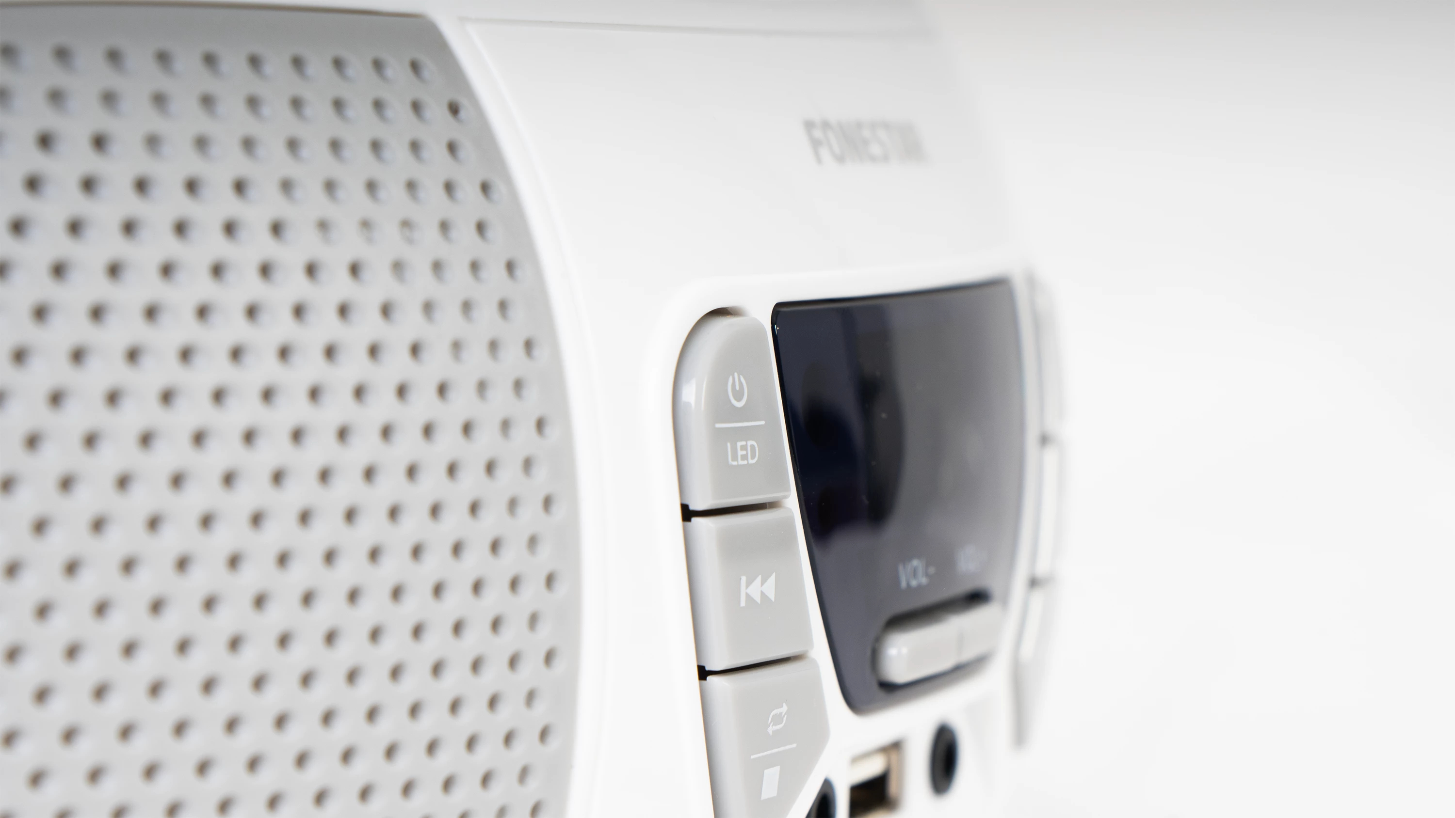 Altavoz blanco con botones de control y pantalla. La palabra 'FONESTAR' es visible.