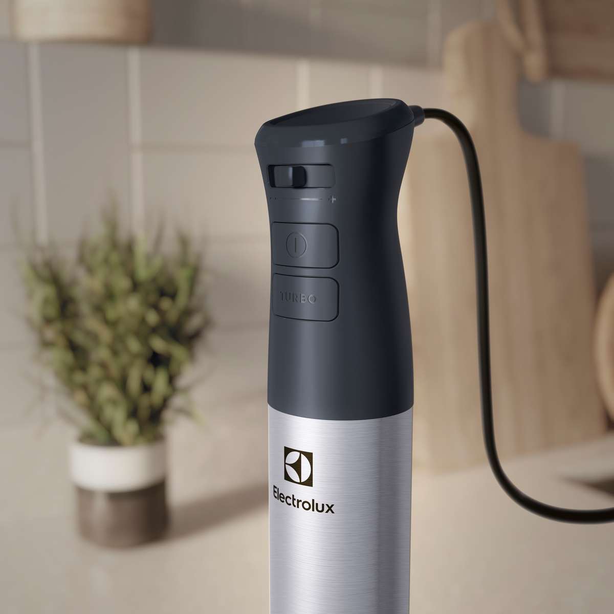 Een Electrolux staafmixer, zilver en zwart, met een netsnoer. Het staat op een aanrecht.