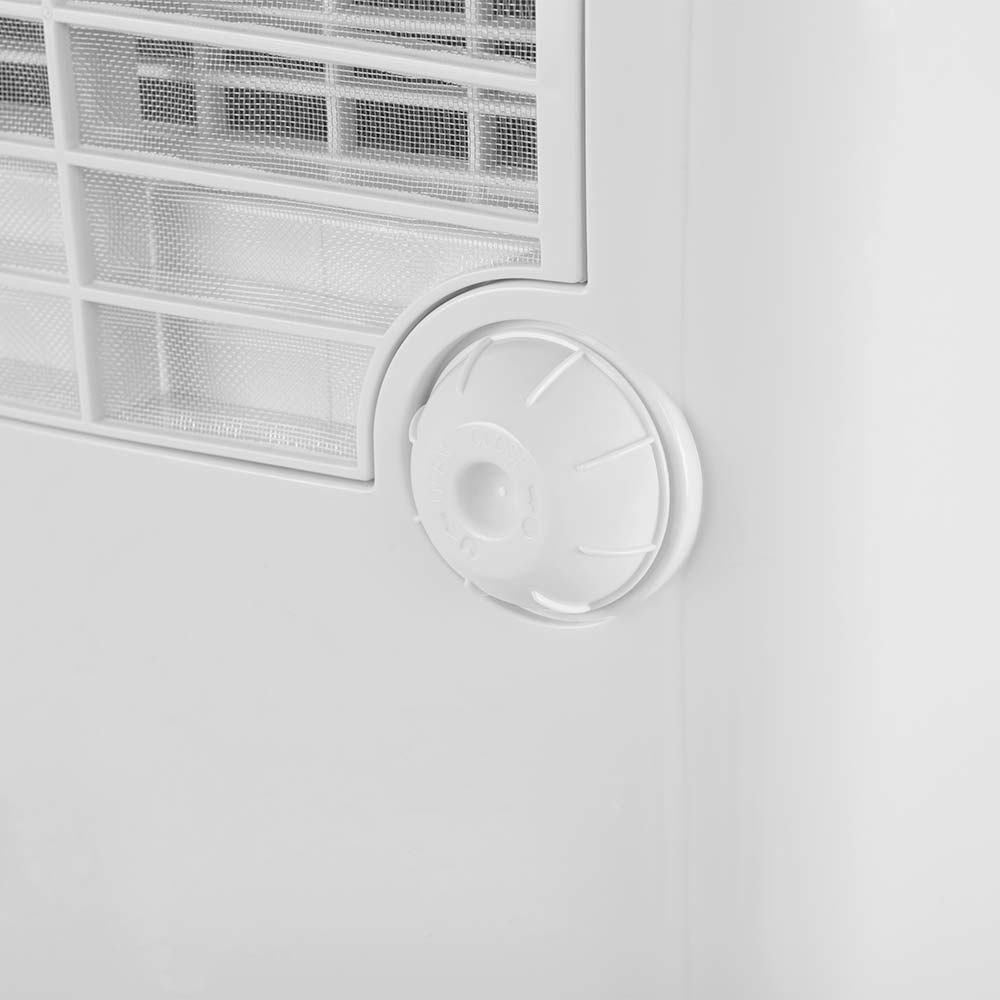 Primo piano di un condizionatore bianco con prese d'aria e un pulsante circolare bianco.