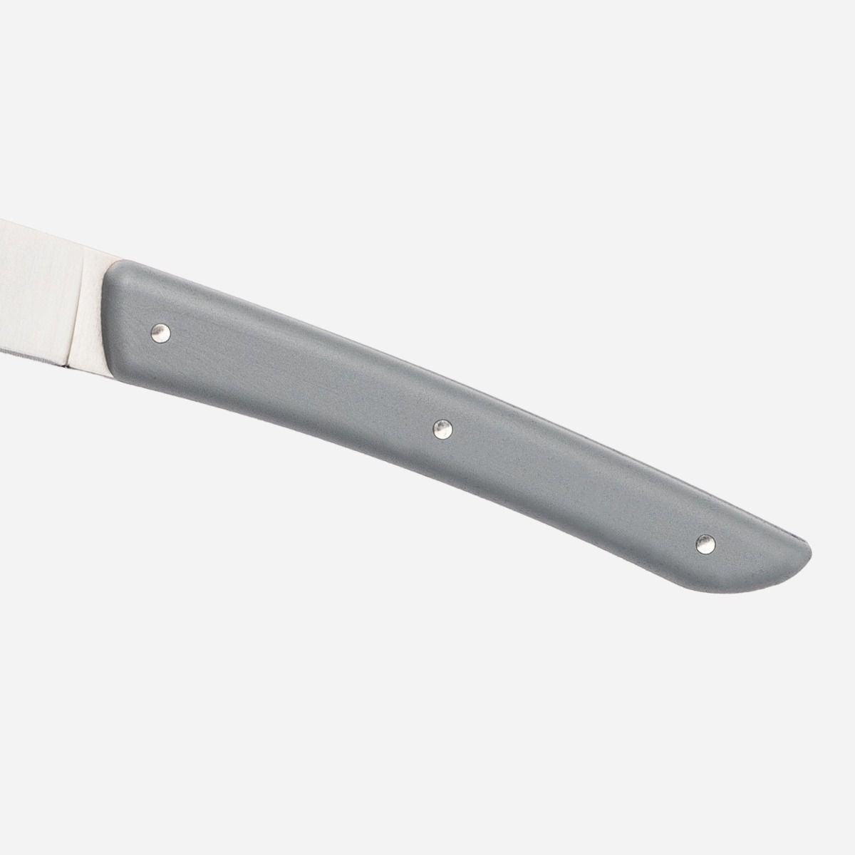Close-up of a knife handle, gray color, with three rivets. The blade is partially visible.