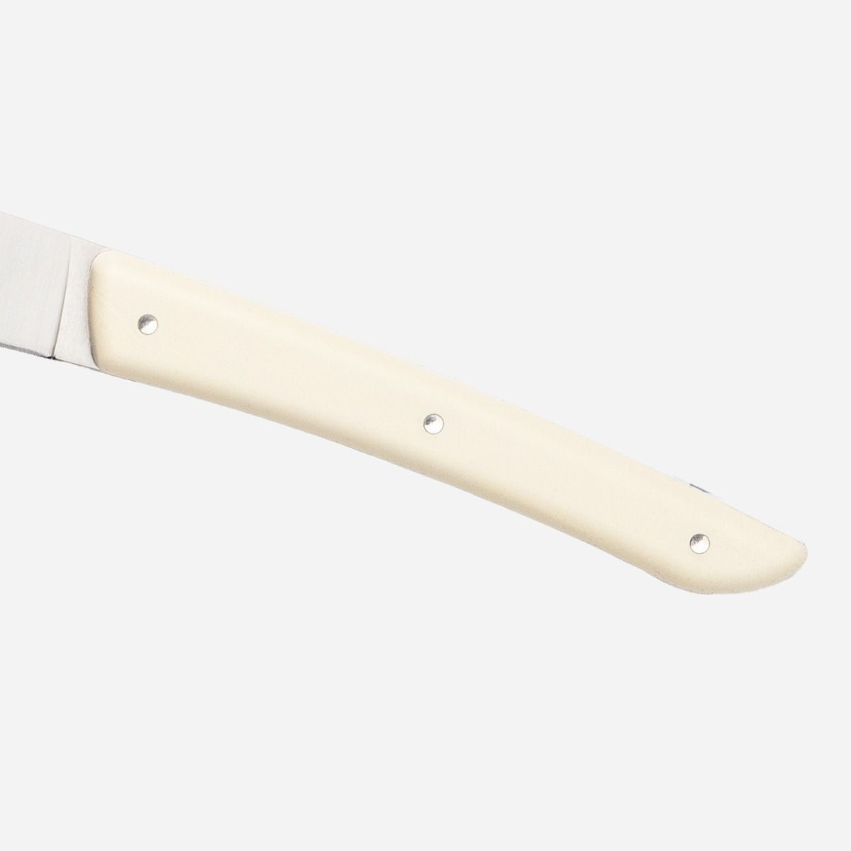 Zbliżenie noża z kremowym uchwytem i srebrnym ostrzem.