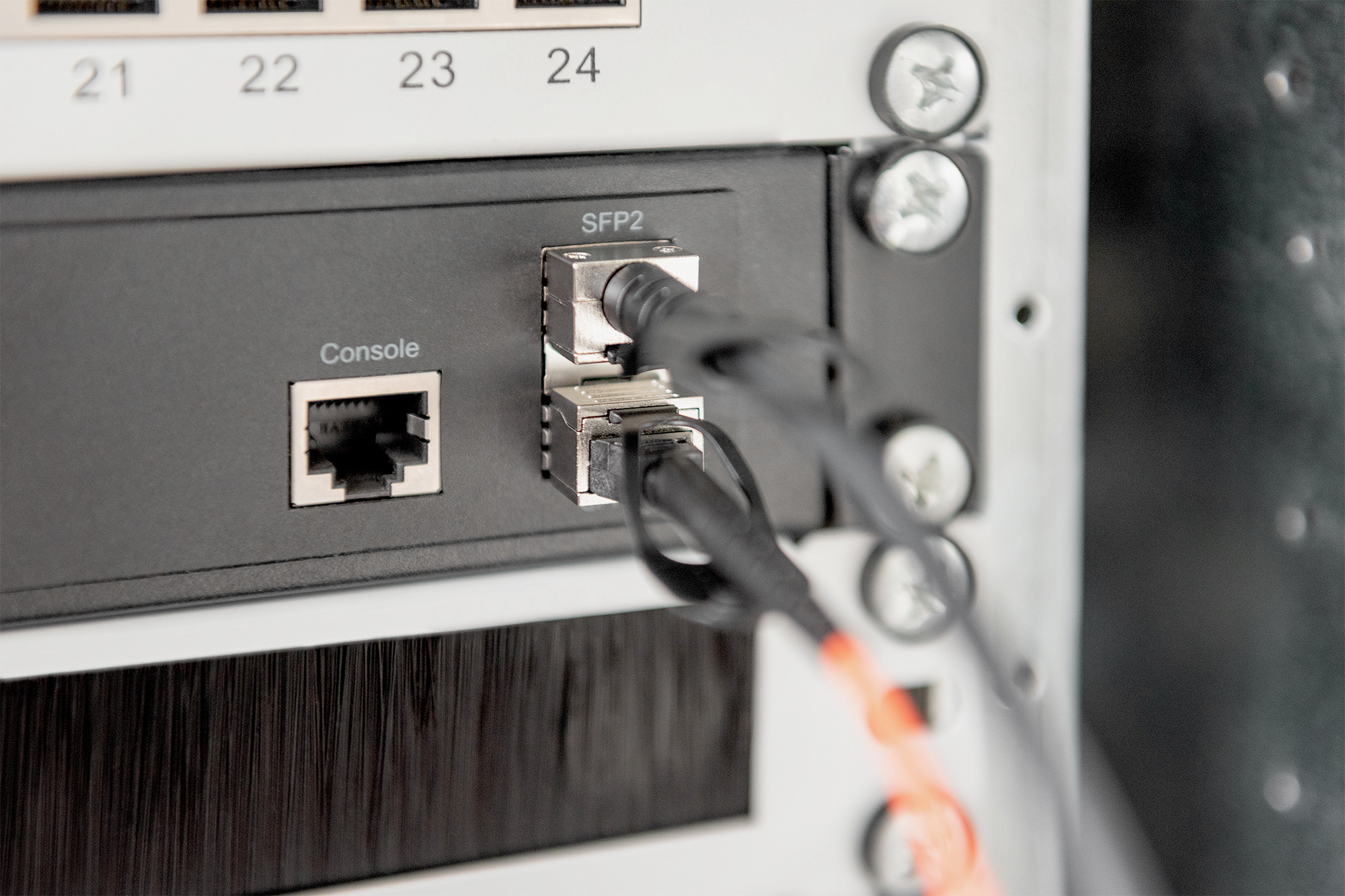 Primo piano di un rack di rete con cavi collegati alle porte console e SFP.