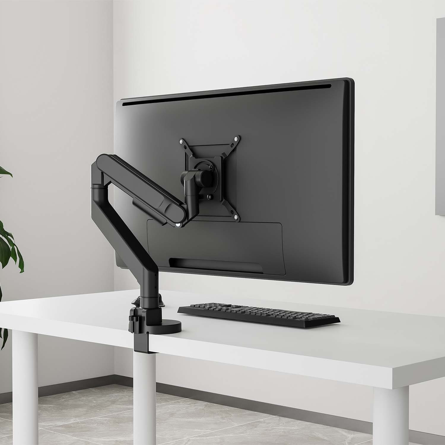 Un monitor en un brazo negro ajustable, sujeto a un escritorio blanco.