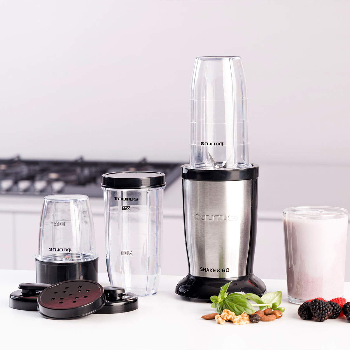 Mixer mit drei Behältern, einem Deckel und einem Glas mit rosa Getränk. Zutaten sind rechts.