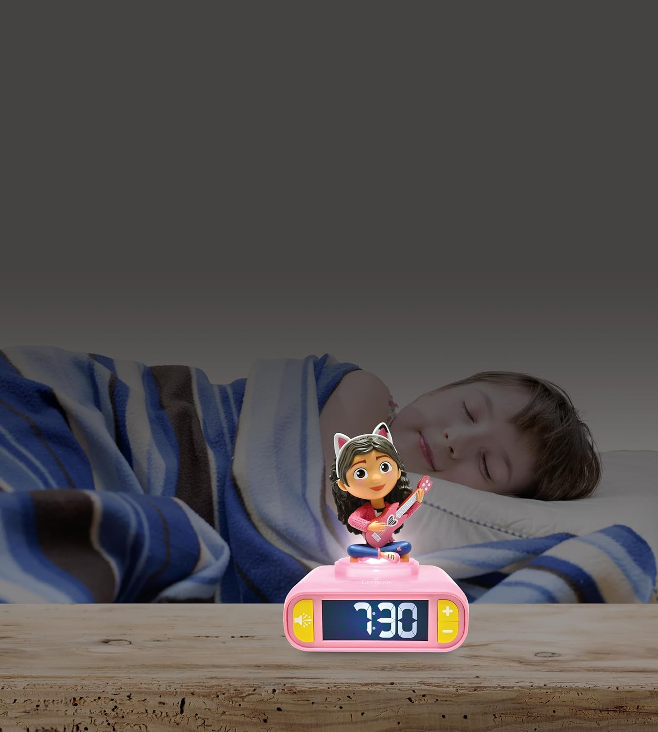 Un niño dormido en la cama con un despertador con una figura de niña en una mesa.