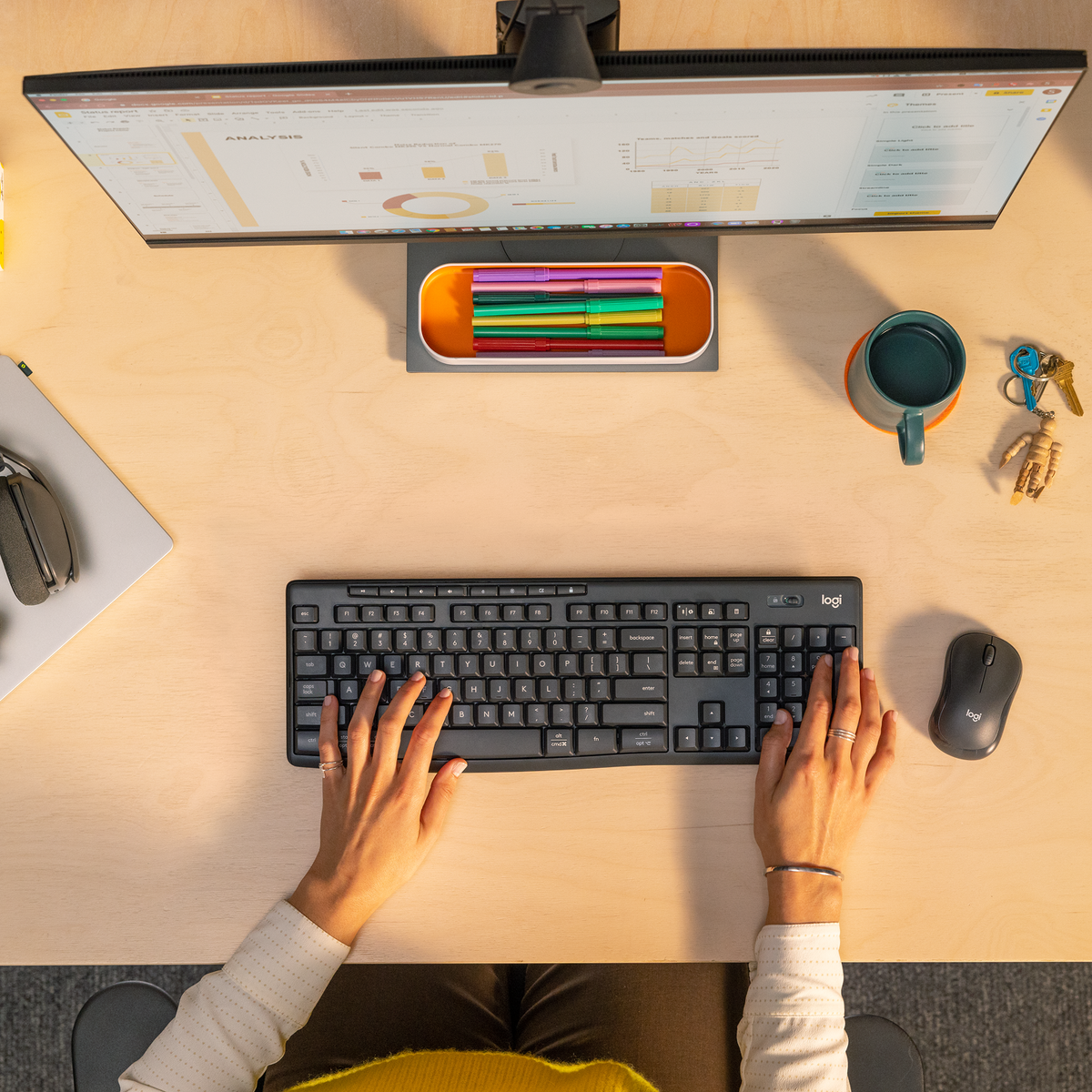 Widok z góry na biurko z klawiaturą, myszą, monitorem i artykułami piśmienniczymi.