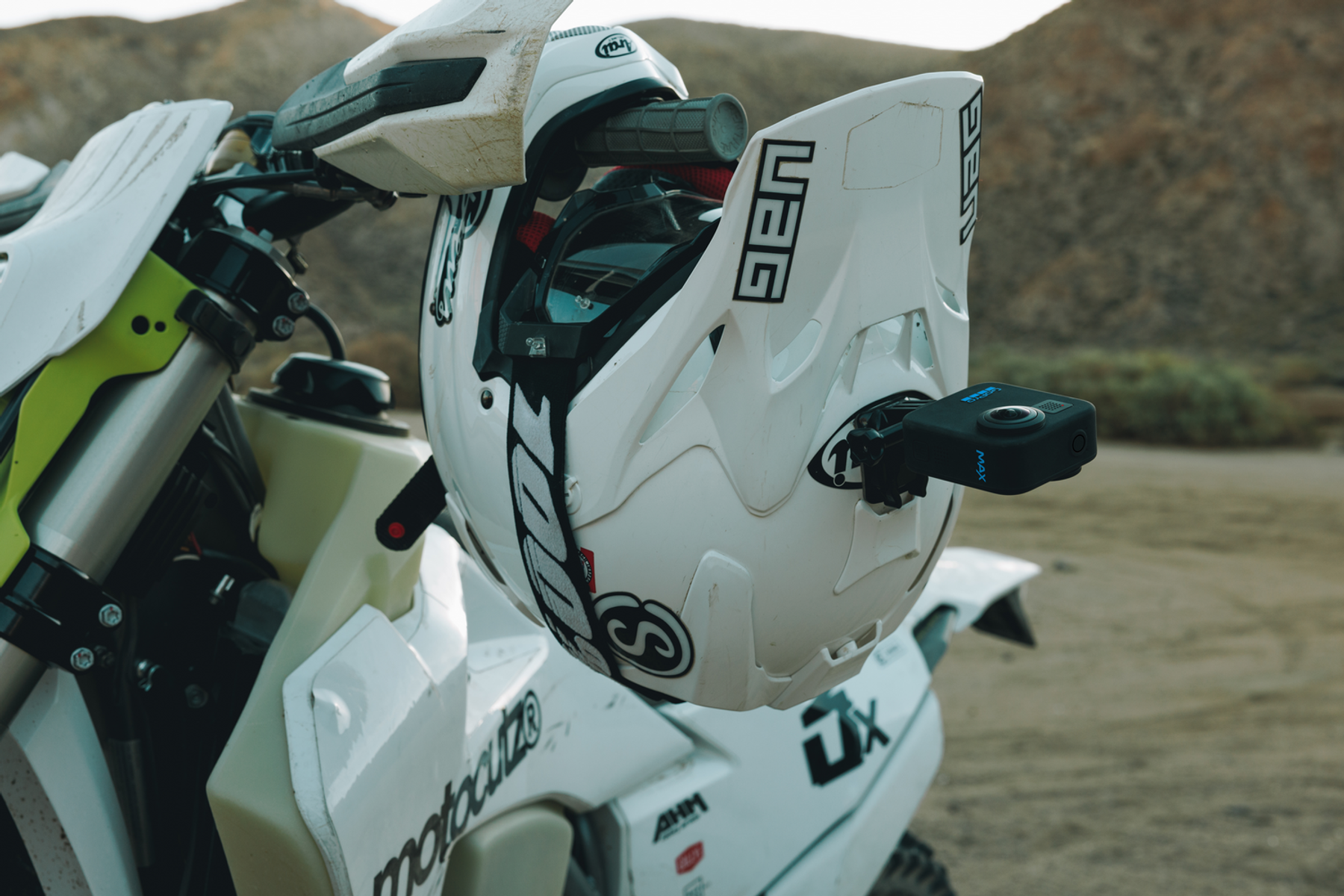 Un casco da moto bianco con una fotocamera GoPro attaccata, montato su una moto da cross.