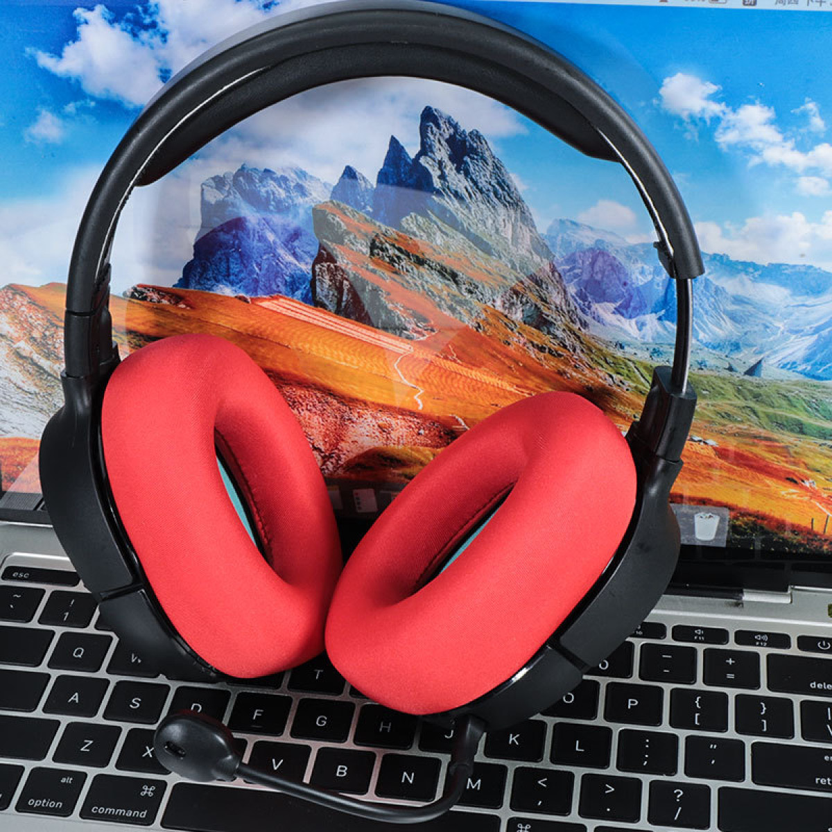Ein Paar roter Kopfhörer mit Mikrofon auf einem Laptop mit einem Landschaftsbild.