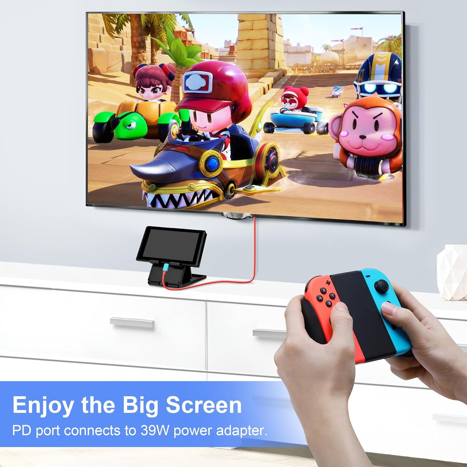 Eine Person hält einen rot-blauen Nintendo Switch-Controller, ein Fernseher zeigt ein Rennspiel.