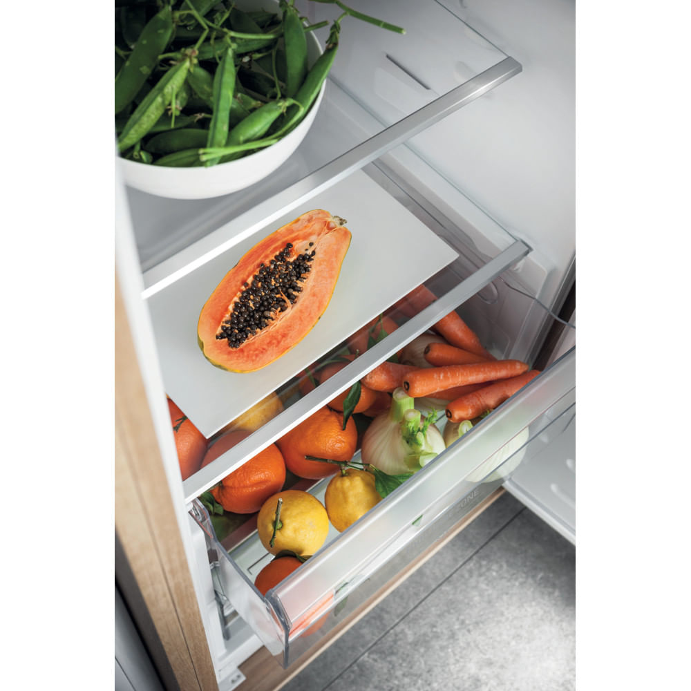 Interno frigorifero con ripiani. Contiene verdure, papaya, arance e limoni. Porta in legno chiaro.