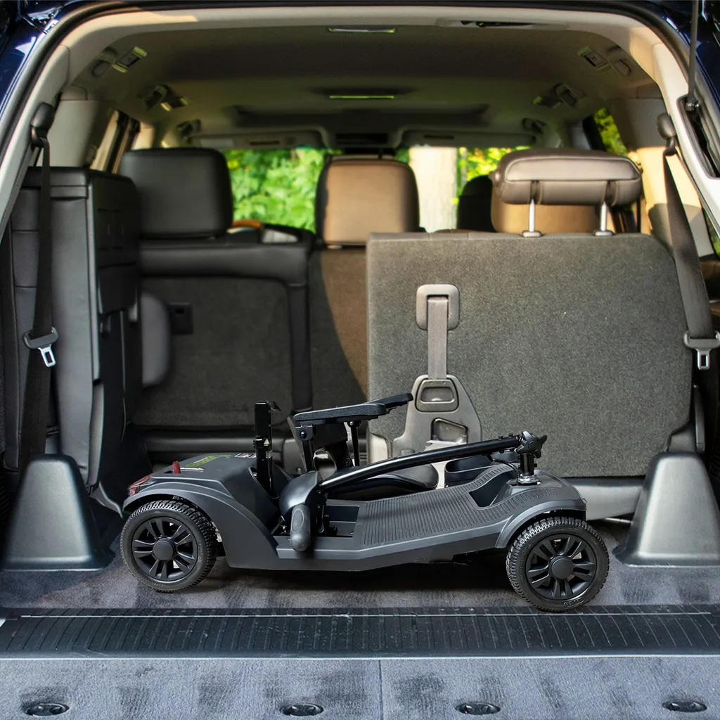Ein schwarzer, zusammenklappbarer Mobilitätsroller im Kofferraum eines Autos. Sitze sind sichtbar.