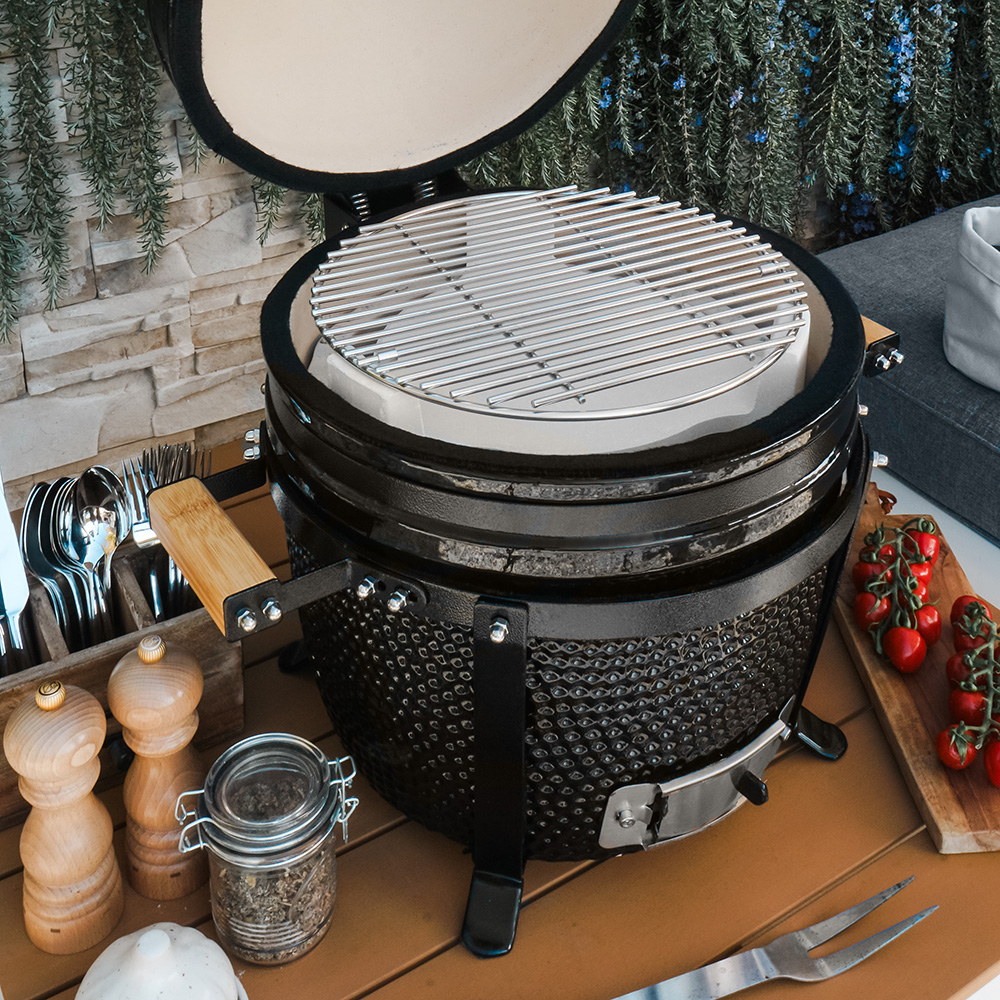 A black grill with a white interior, surrounded by cooking utensils and food.