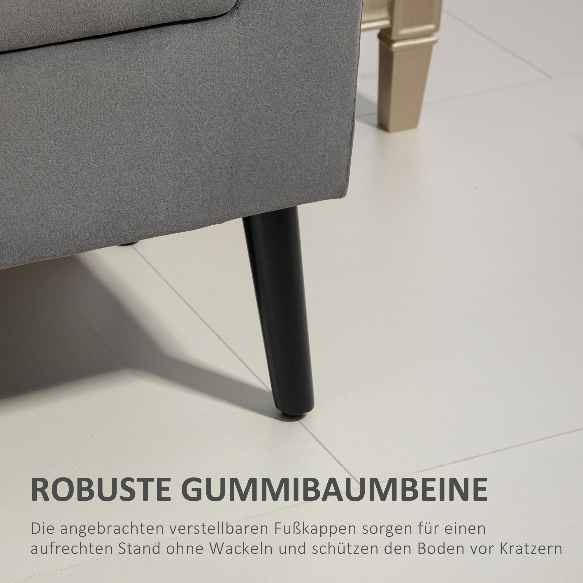 Nahaufnahme eines grauen Sofabeins mit schwarzem Bein und weißem Boden. Text unten.