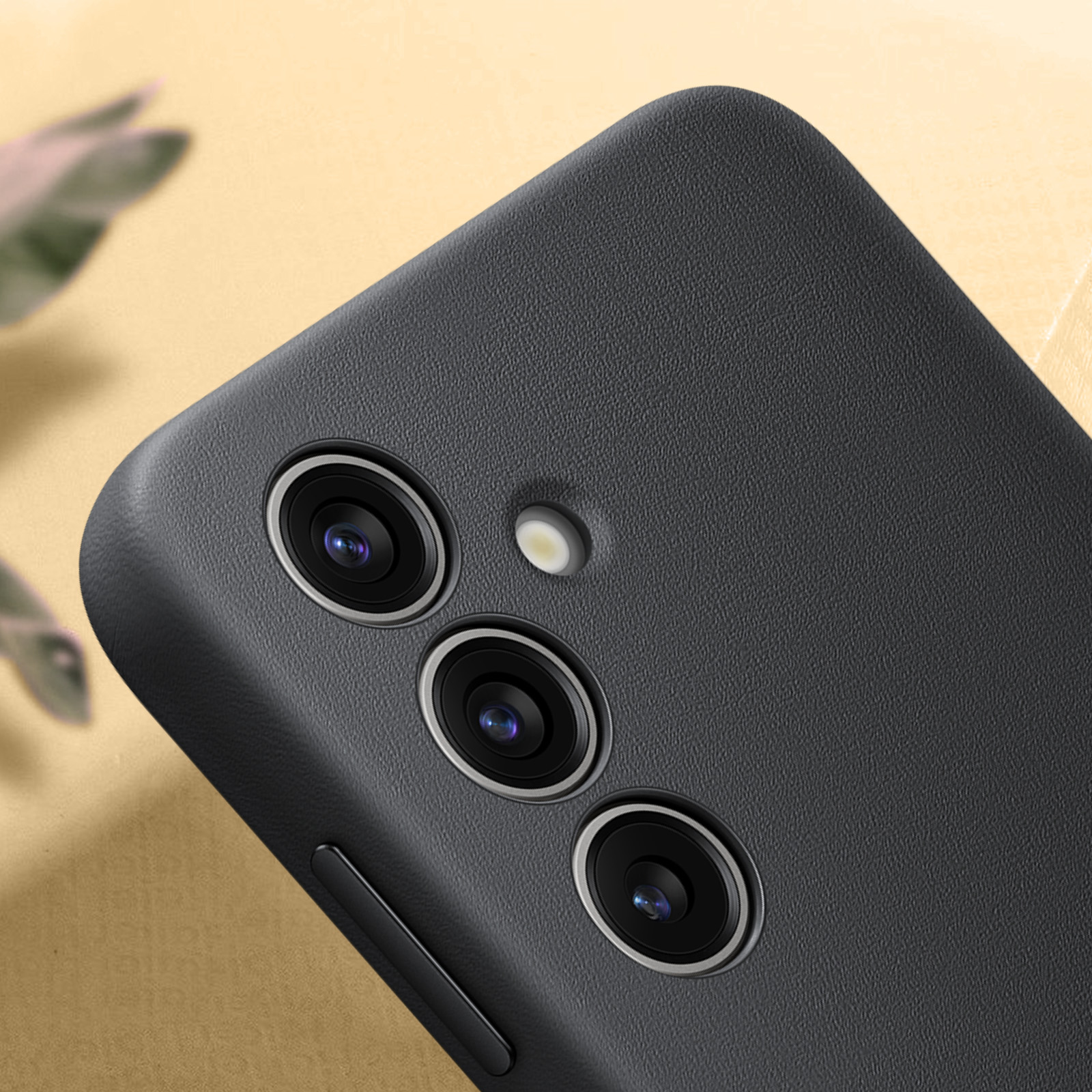 Zbliżenie czarnej obudowy telefonu z trzema obiektywami aparatu i lampą błyskową. Obudowa jest teksturowana.
