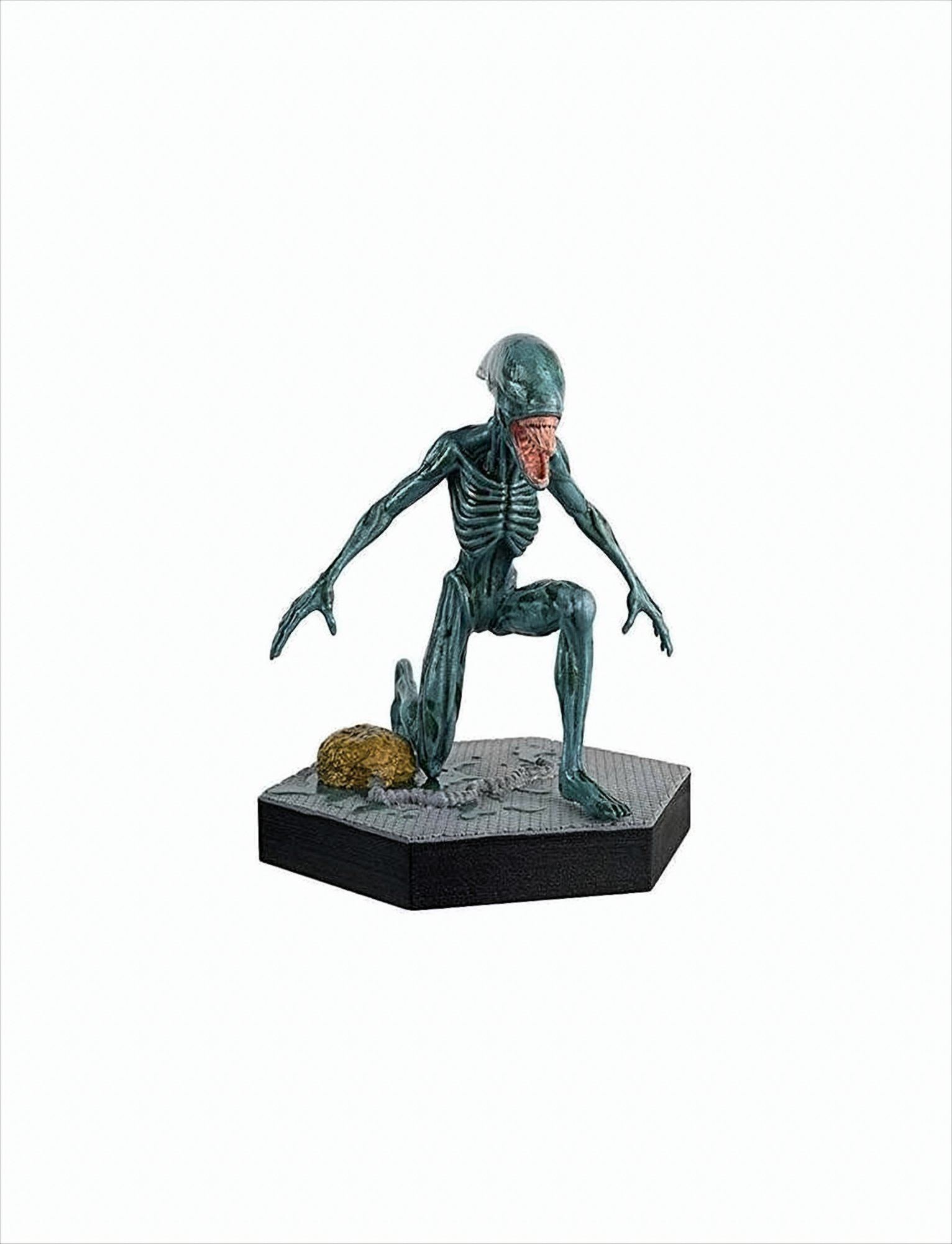 Eine grüne Alienfigur auf schwarzem Sockel. Sie kniet auf einer grauen Oberfläche.