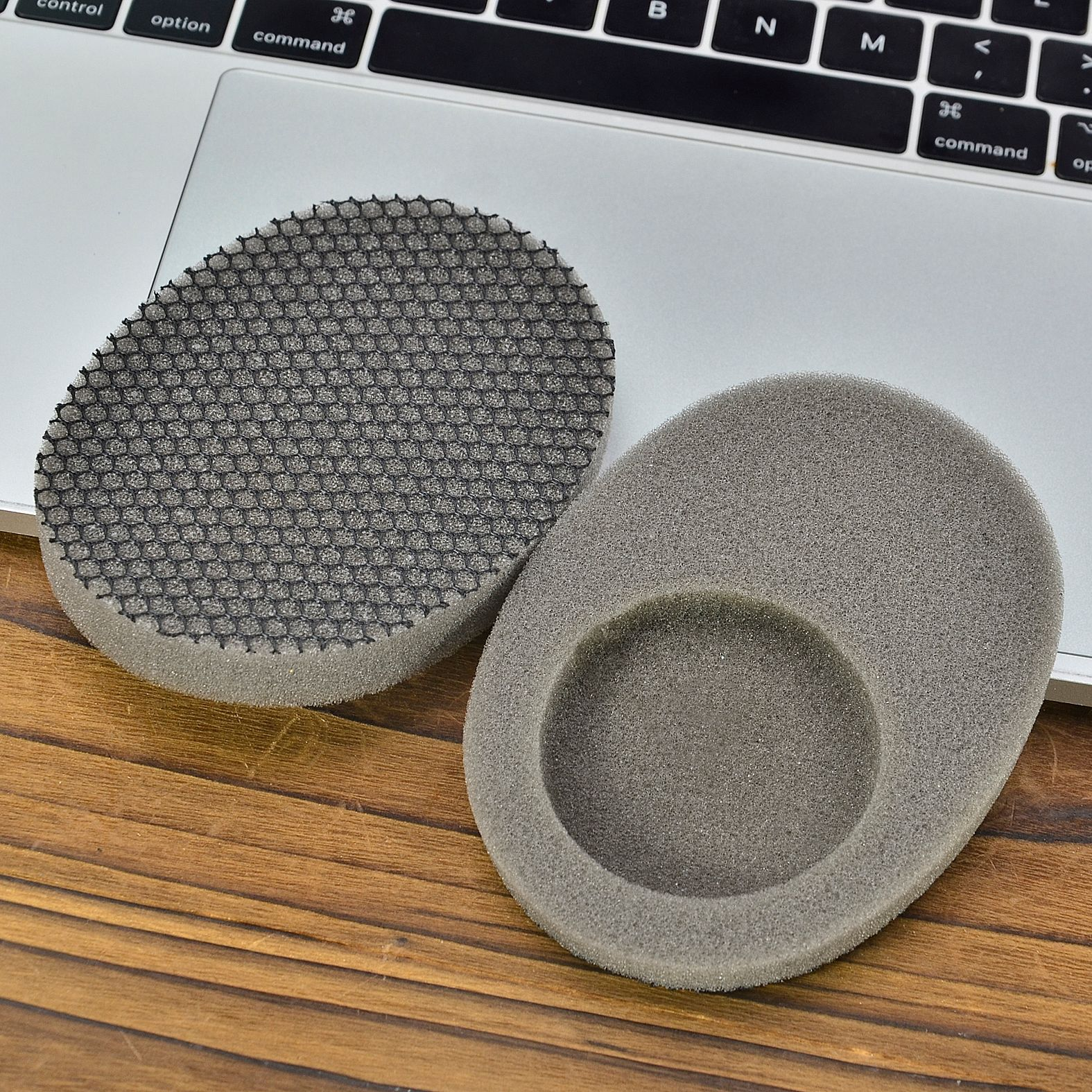 Zwei Schaumstoffpads auf einer Holzoberfläche, die auf einer Laptop-Tastatur platziert sind.