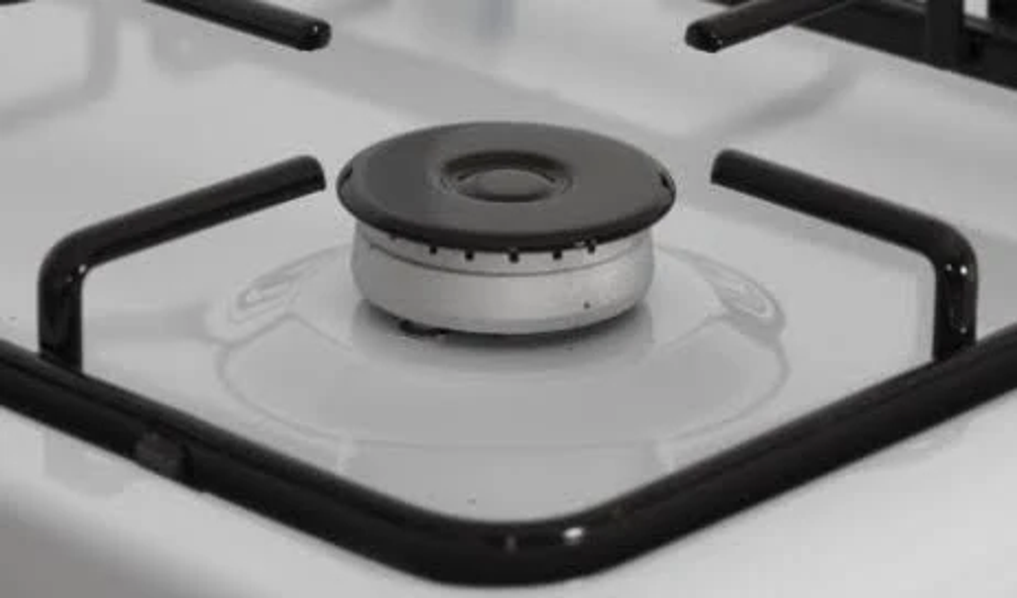 Primer plano de un quemador de estufa de gas con soporte negro y quemador central.