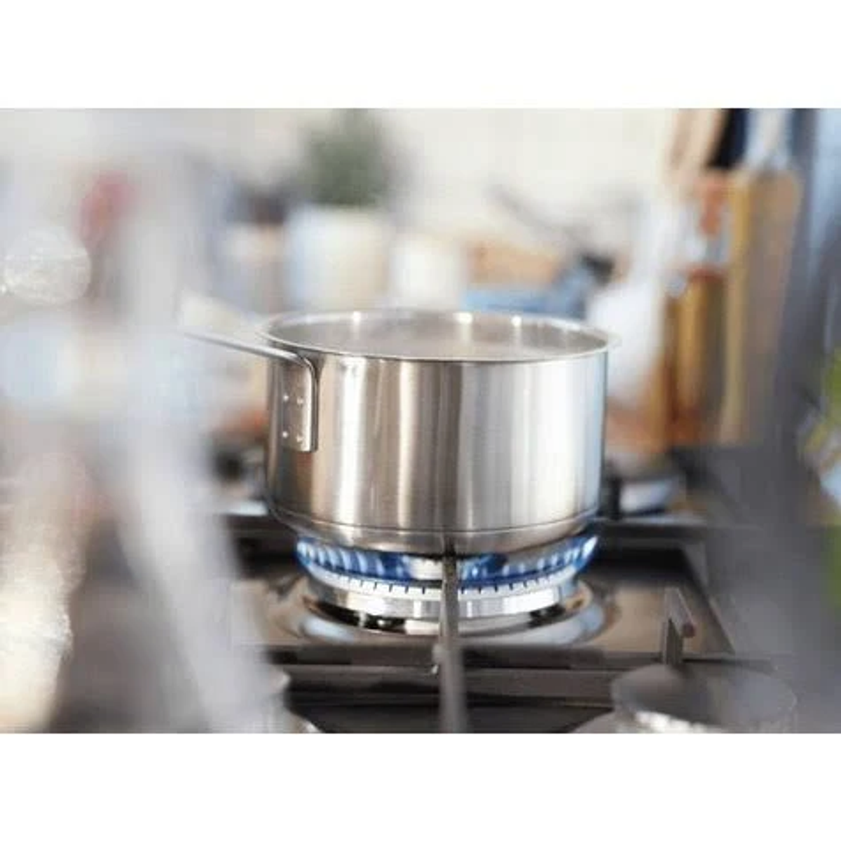 Una olla de acero inoxidable en una estufa con una llama azul.