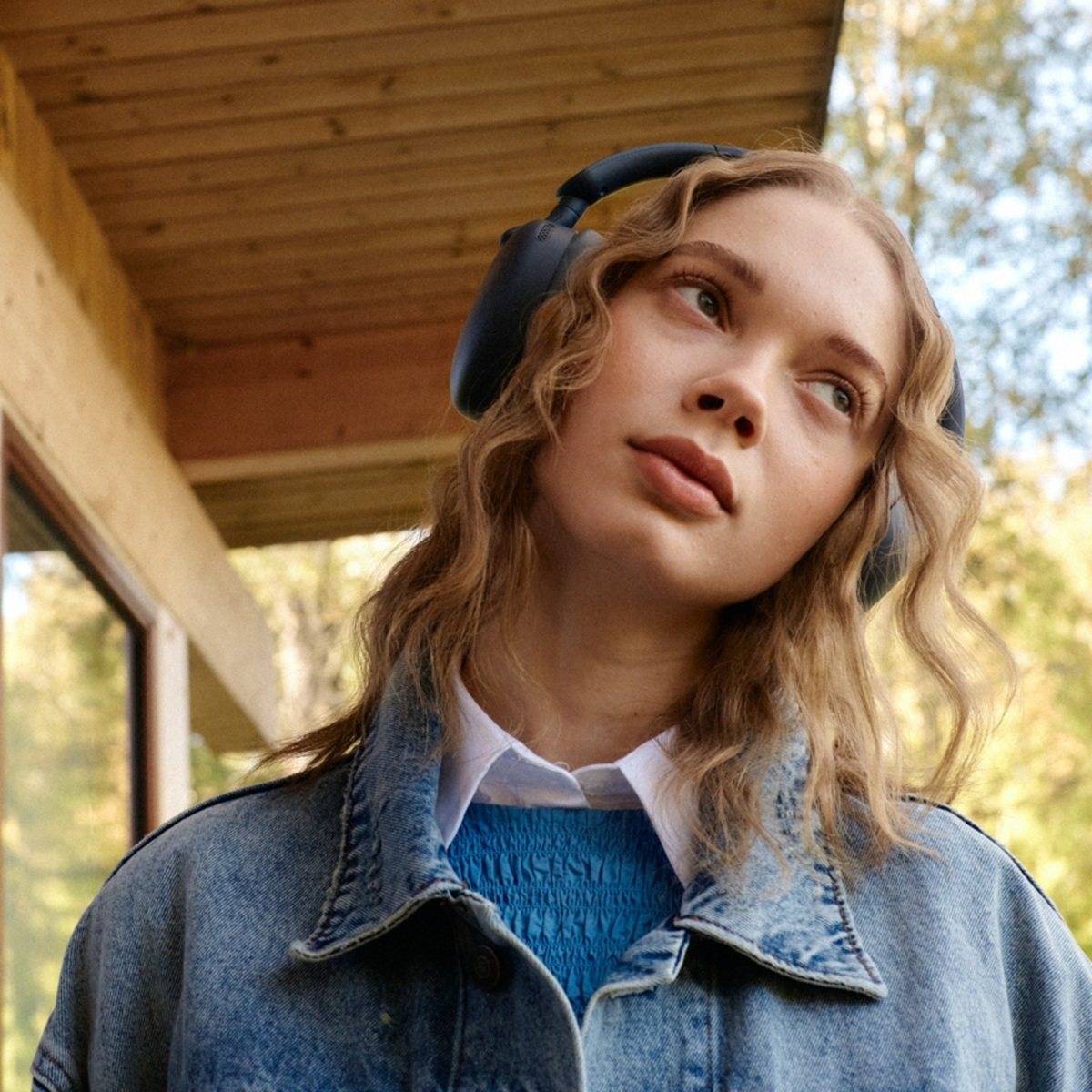 Jeune femme avec un casque, regardant en l'air, portant une veste en jean.