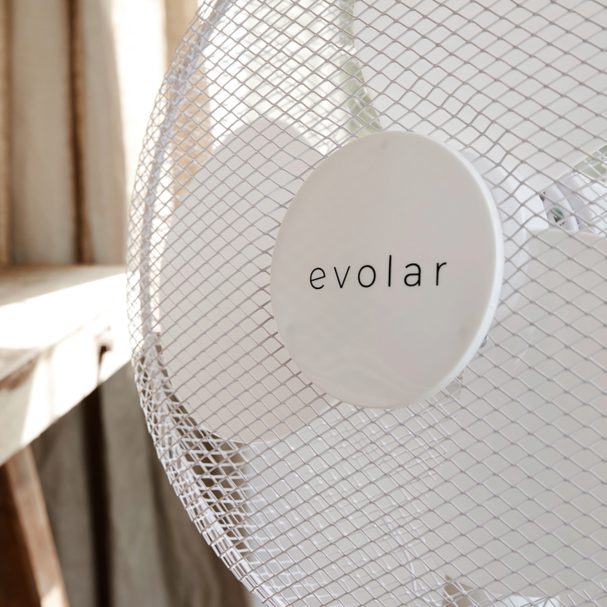 White desk fan with a mesh grill. The word 'evolar' is printed on the center.
