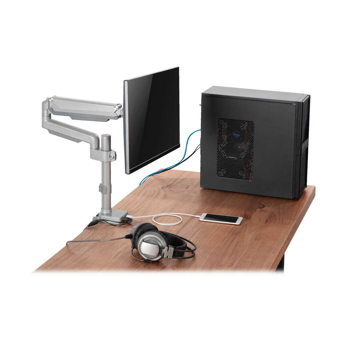 Konfiguracja komputera: monitor, wieża PC, ramię monitora, biurko, słuchawki i kable.