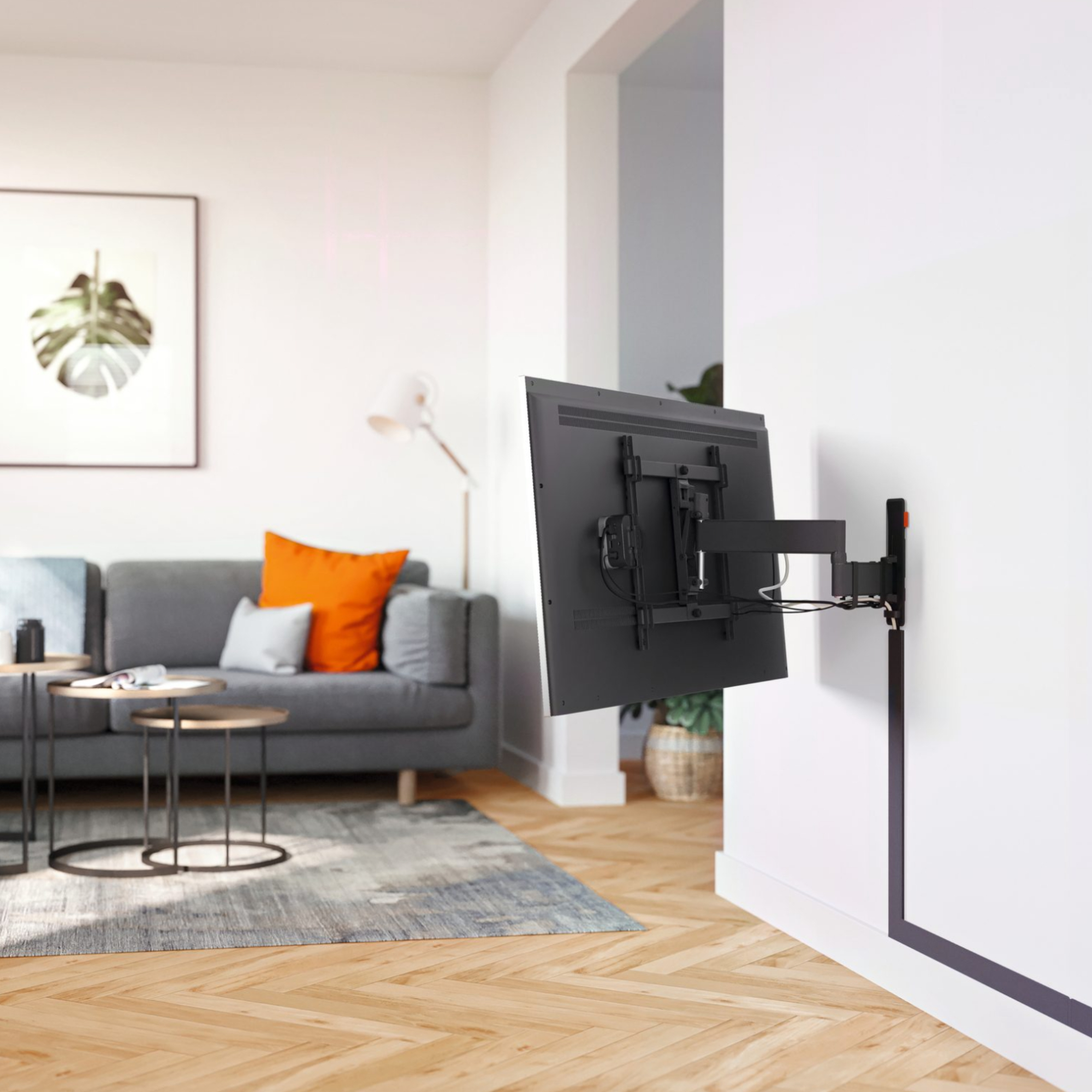 Fernseher an der Wand, graues Sofa und Dekoration im Hintergrund.
