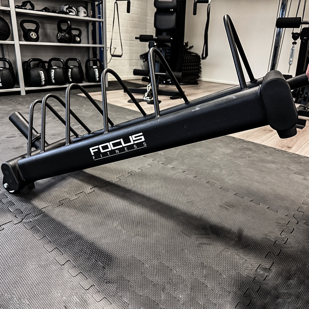 Zwart gewichtenrek met gewichten. Focus Fitness logo. Gym omgeving.