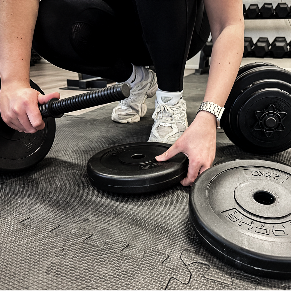 Person with weights. Black weights on a black mat in a gym.