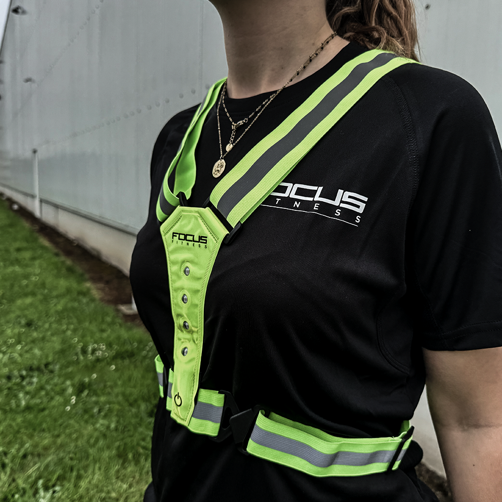 Vrouw met neon groen vest met reflecterende strepen. Zwart shirt.