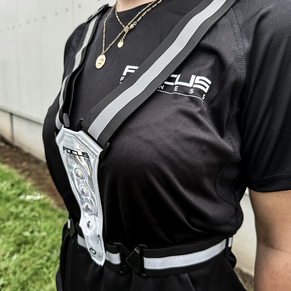 Persoon met een borstband. Focus Fitness logo op het shirt. Grijze reflecterende strips.