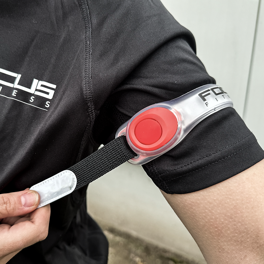 Persoon die een zwart shirt draagt ​​met een armband. De armband is zwart en rood met een reflecterende strip.