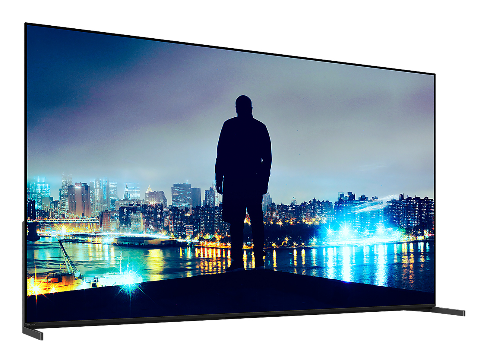 Un hombre frente a una pantalla de TV gigante que muestra una ciudad de noche.