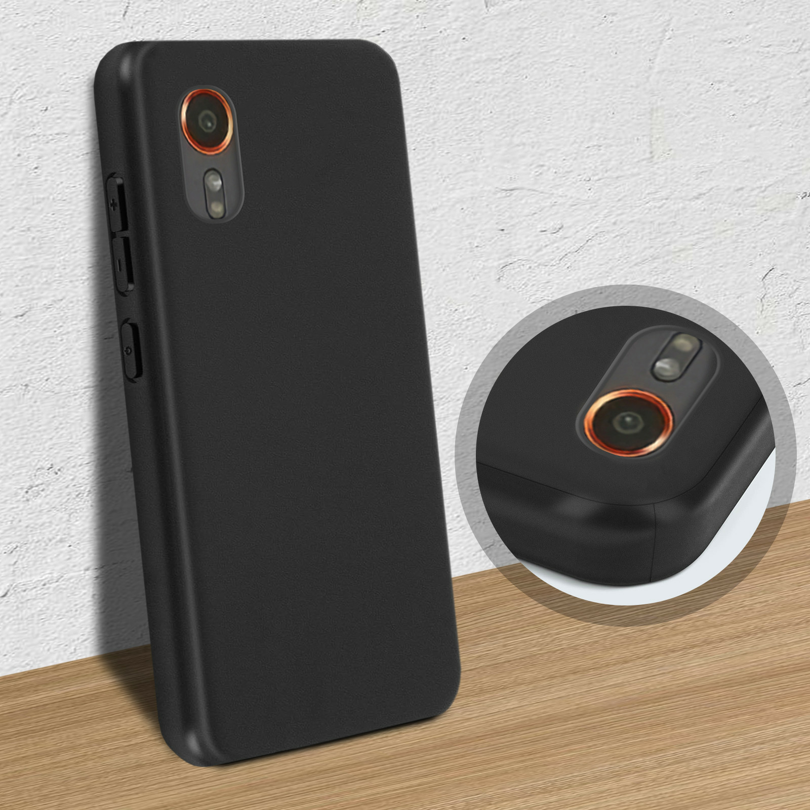 Telefono nero in una custodia nera. Il telefono ha una doppia fotocamera. Appoggiato a un muro.