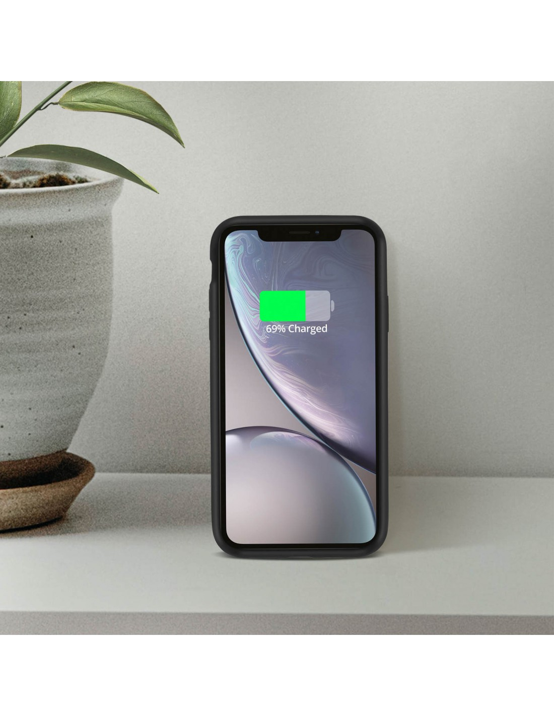 Ein iPhone in einer schwarzen Hülle, das auf einer weißen Oberfläche geladen wird. Der Bildschirm zeigt 69 % geladen.