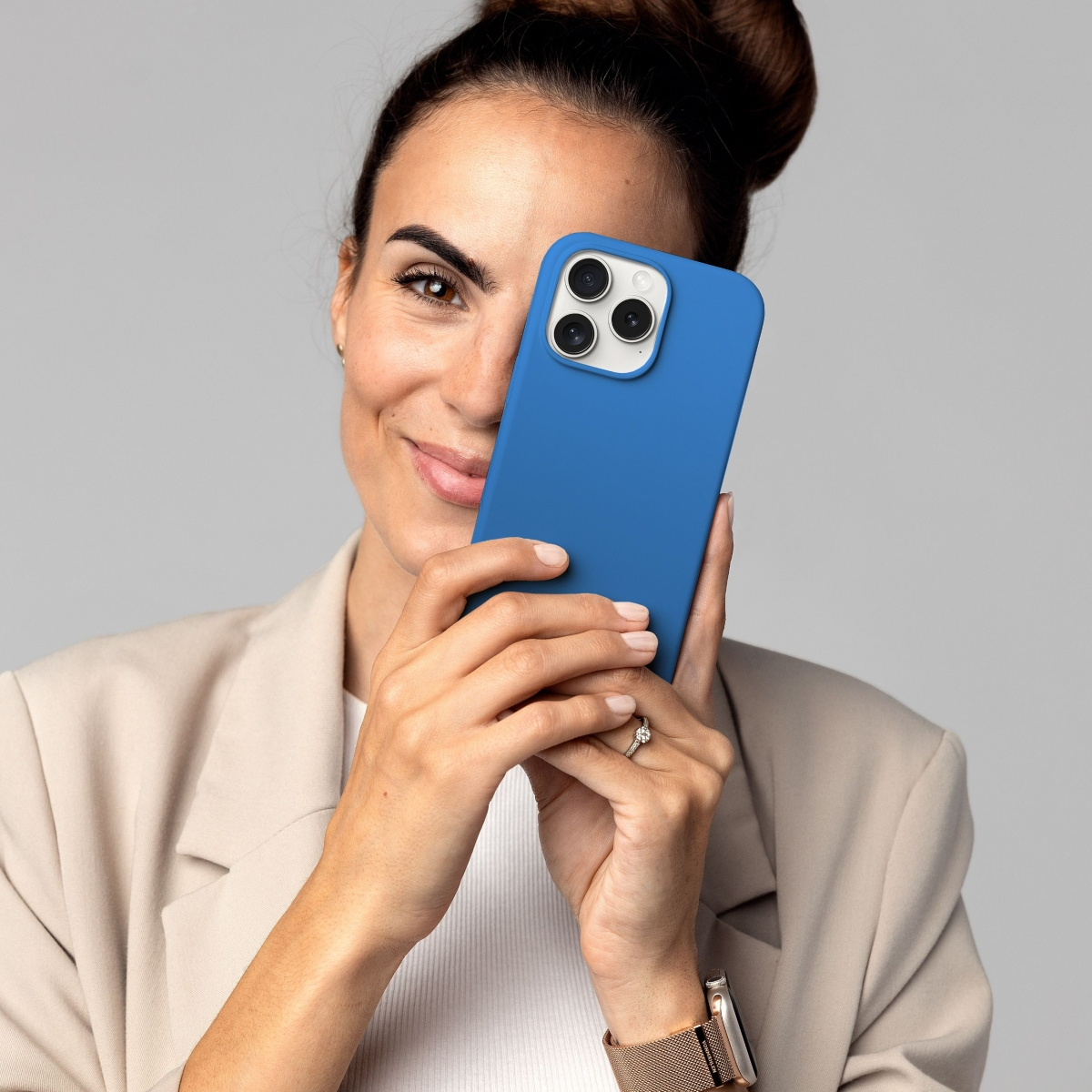 Donna sorridente, tiene in mano telefono blu con custodia blu.