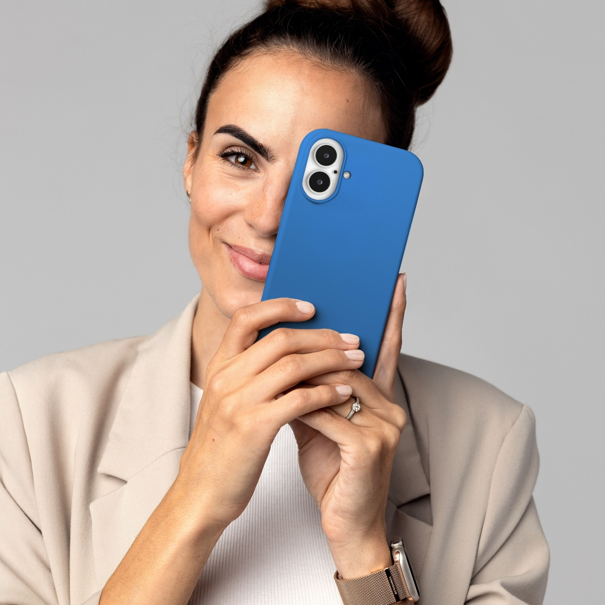 Eine Frau hält eine blaue Handyhülle und bedeckt ihr Gesicht damit, lächelnd.