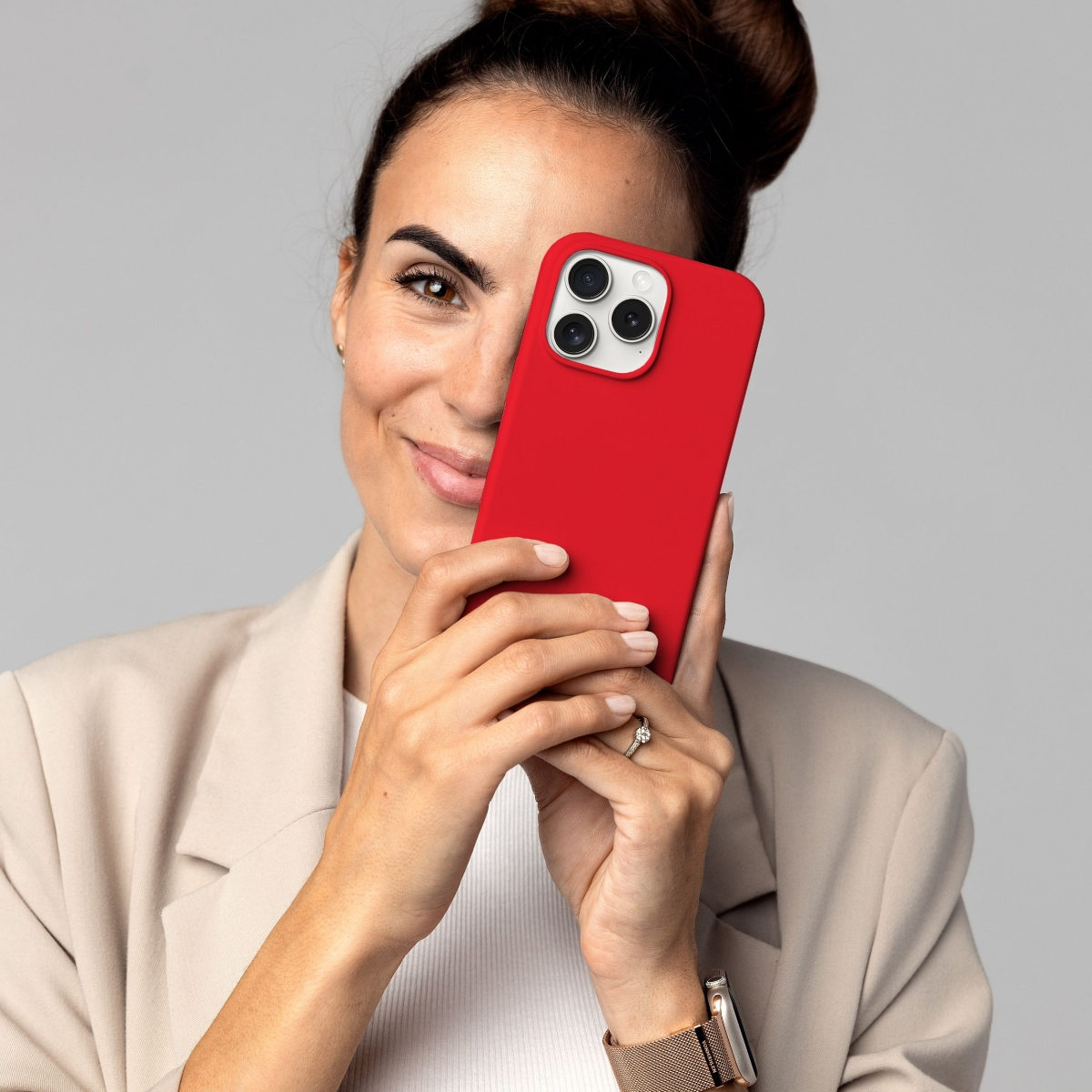 Donna che tiene una custodia rossa per telefono che le copre il viso, su sfondo bianco.