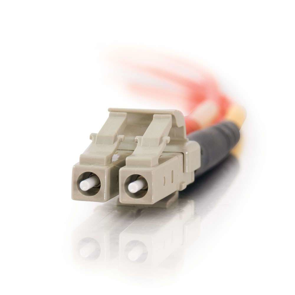 Primer plano de un conector de fibra óptica beige con dos puertos sobre una superficie blanca.