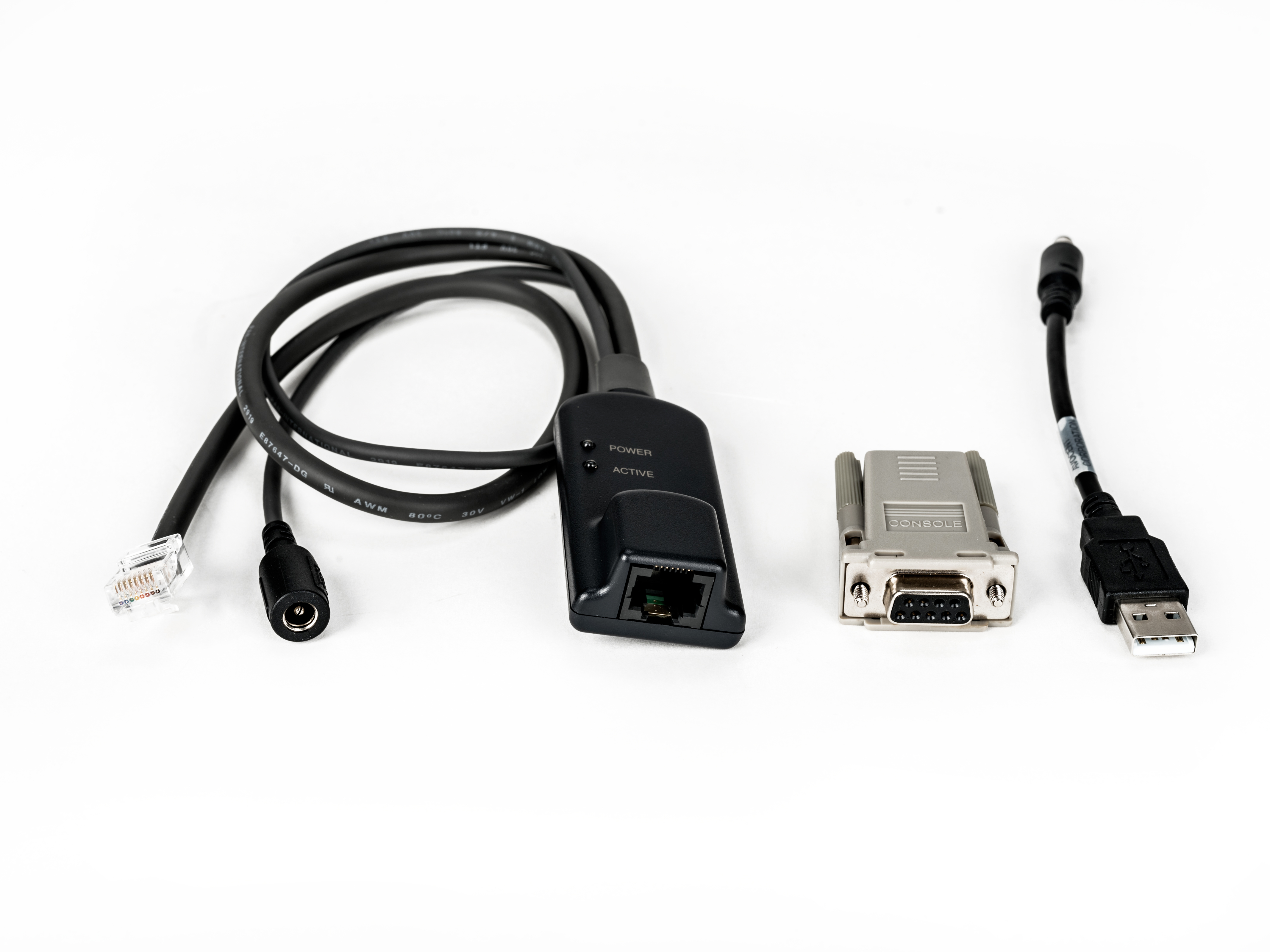 Vari cavi e connettori su sfondo bianco. Include un connettore di alimentazione, una porta console e un cavo USB.