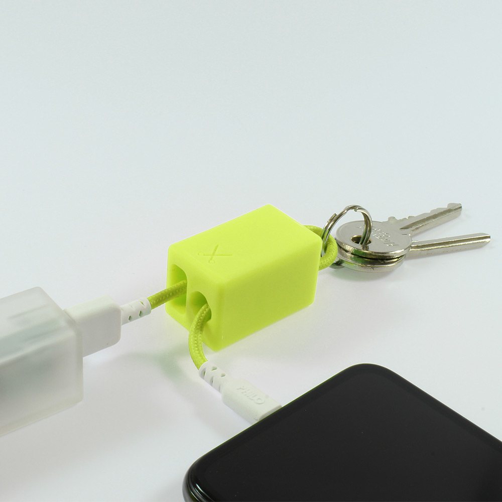 Blocco verde lime con cavi e chiavi, collegato a un telefono e un caricabatterie, su sfondo bianco.