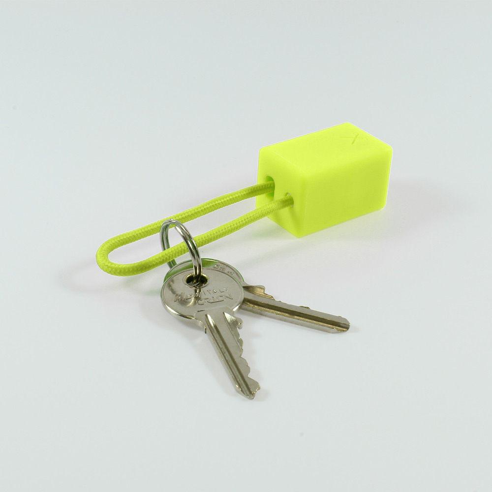 Un blocco giallo con un anello di corda verde e due chiavi attaccate a un anello d'argento.