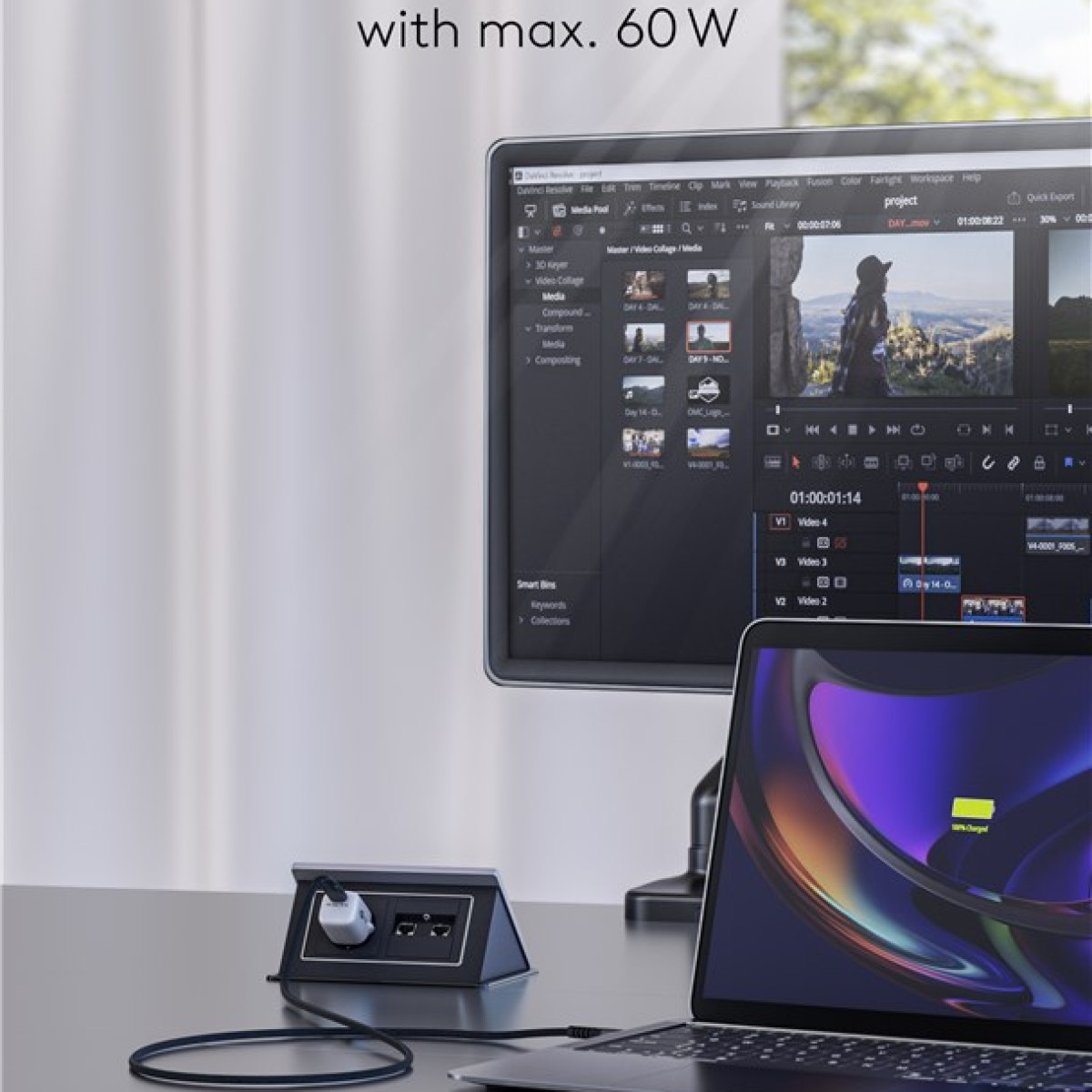Un laptop con icona di ricarica e un monitor che mostra un software di video editing collegato a un dock nero.