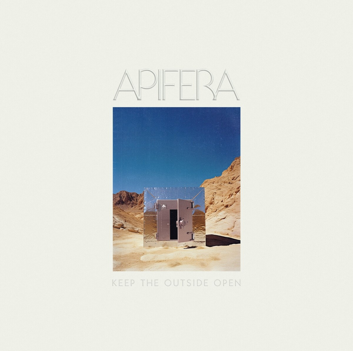 Copertina dell'album: Edificio metallico in un paesaggio desertico sotto un cielo blu. Testo: APIFERA, Keep the Outside Open.